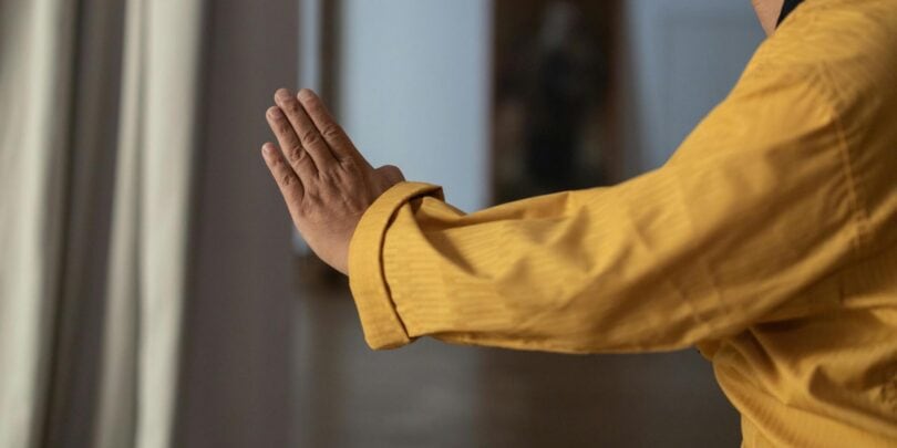 Person in gelber Jacke praktiziert Schweigemeditation im Freien, Fokus auf Achtsamkeit und innere Ruhe. Perfekt für Stressabbau und spirituelle Praxis.